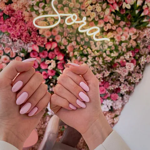 Sora Beauty Studio çiçek duvarı ve neon logosu önünde pastel pembe badem kalıcı oje — Suadiye